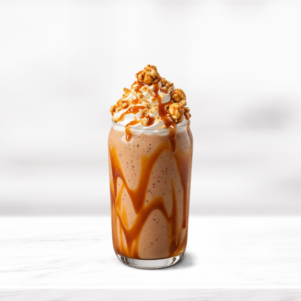 Creamy butterscotch smoothie topped with whipped cream, caramel sauce and caramel popcorn